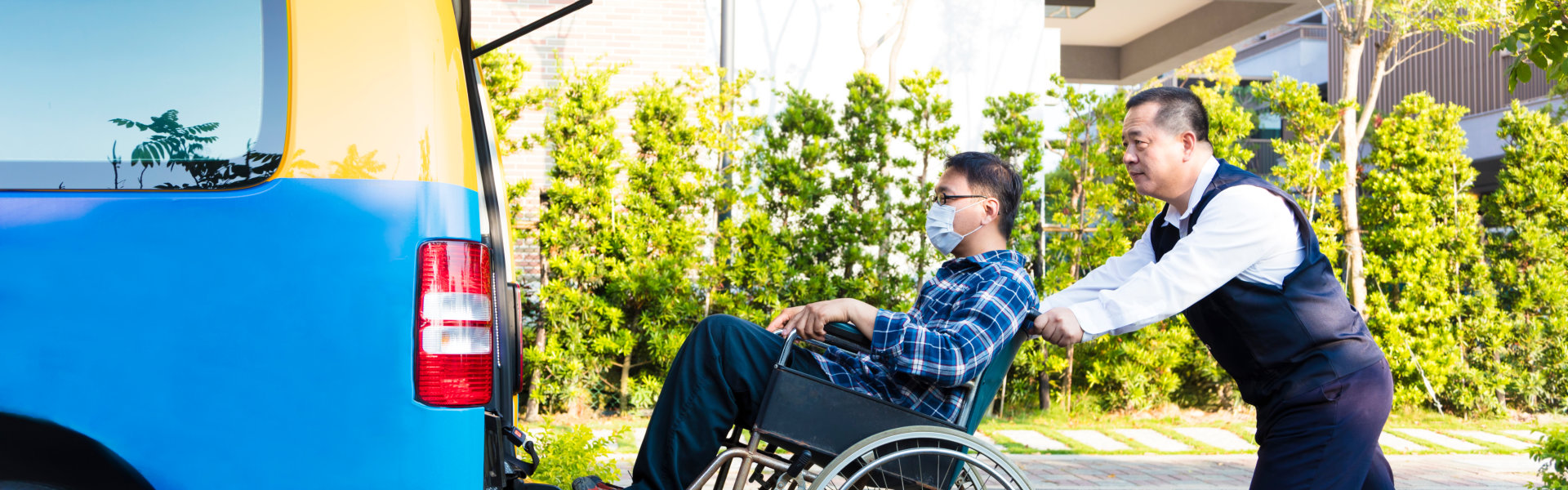 man assisting an person in a wheelchair to get on the car